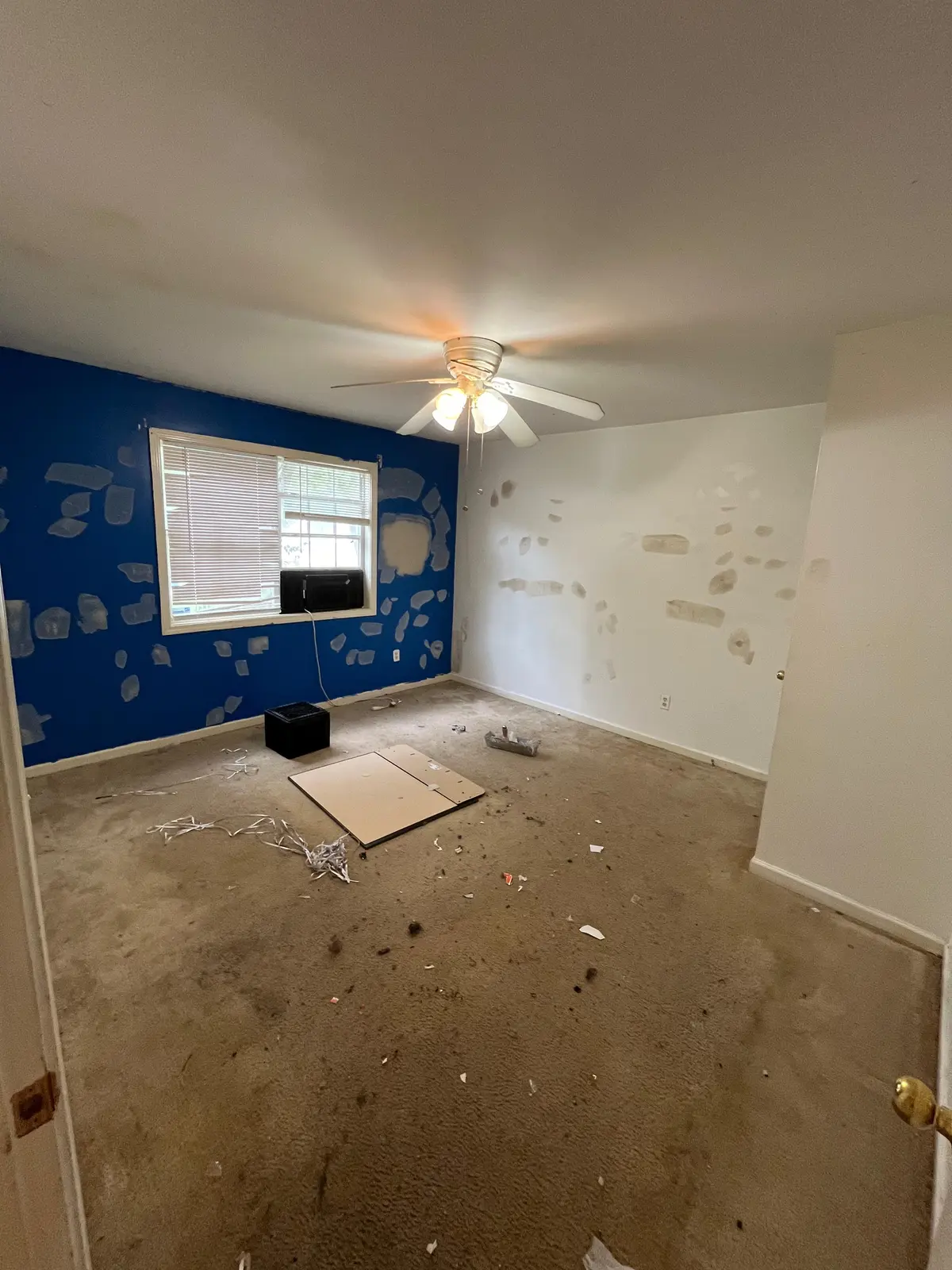 Bedroom before painting: blue accent wall with patched drywall
